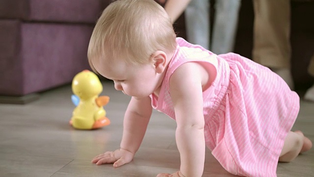 漂亮的婴儿在家里的地板上爬。幸福的家庭的概念视频下载