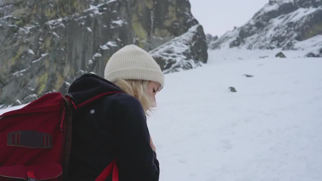 冬天在冰雪覆盖的岩石山脉徒步旅行视频购买