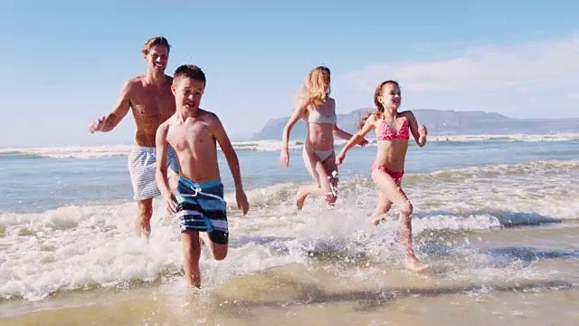 暑假里，父母和孩子们穿着泳装从海里跑出来视频素材