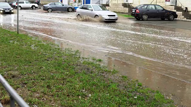 雨中，汽车在满是脏水的道路上行驶。视频素材