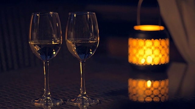 两个白葡萄酒酒杯和灯笼，桌上点着蜡烛。视频素材