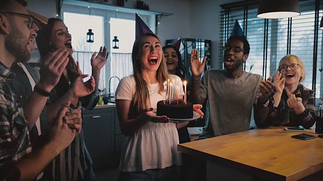 快乐兴奋的白人女孩拿着生日蛋糕，多民族朋友唱着欢快的歌曲，在欢乐的派对上慢镜头视频素材