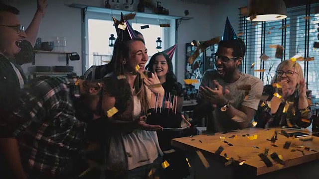 快乐的欧洲女孩拿着生日蛋糕，许愿和吹，多民族的朋友唱歌在有趣的派对慢镜头视频素材