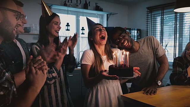 快乐的白人女孩拿着生日蛋糕，在欢乐的多民族聚会与朋友慢镜头4K许愿视频素材
