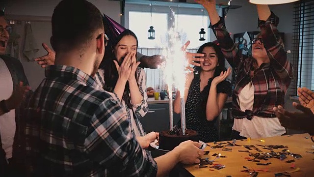 生日快乐的女孩反应在闪闪发光的烟花蛋糕在惊喜庆祝派对与多民族的朋友慢动作视频素材