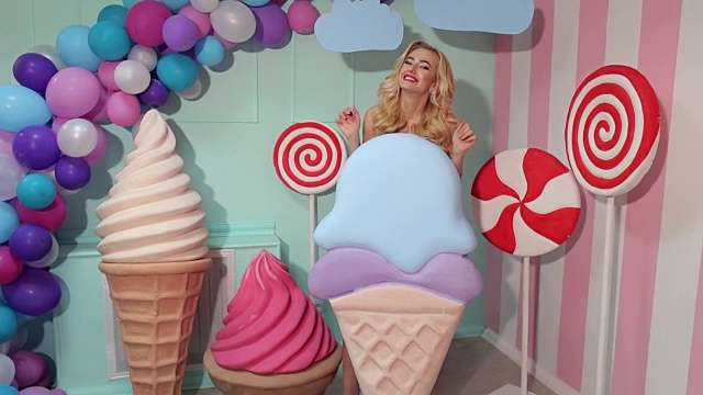 女孩拿着巨大的冰淇淋在五颜六色的工作室。视频下载