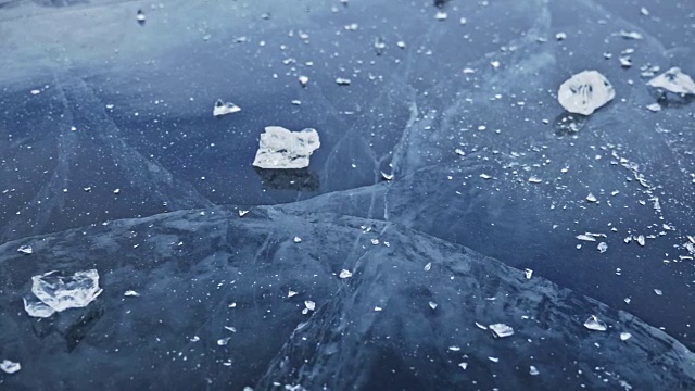 戴手套的人在冰上打碎冰。缓慢的运动。镜头移到了冰的后面。一块美丽的冰在冰的周围裂开，有神奇的裂缝。冰冻水的颗粒。视频素材