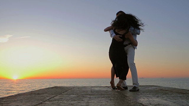在日出和大海的背景下，一对精力充沛的西班牙夫妇展示着性感的拉丁舞元素:巴塔舞(bachata)、伦巴舞(rumba)或kizomba。慢动作视频素材