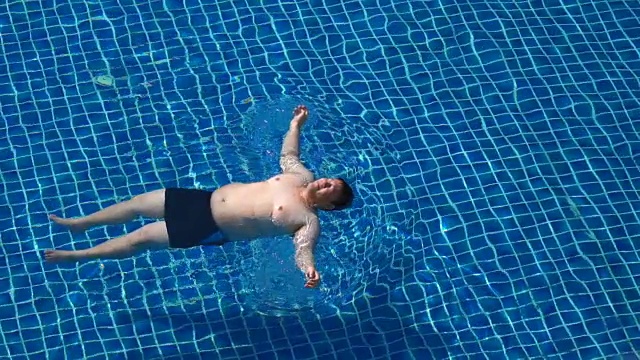 超重男子游泳海星浮在游泳池视频下载