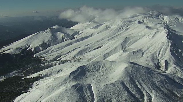 在白雪皑皑的山峰上空，蒸汽从火山口升起。日本。视频素材