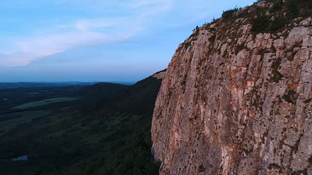 鸟瞰图沿着陡峭的垂直悬崖在山谷日落。视频素材