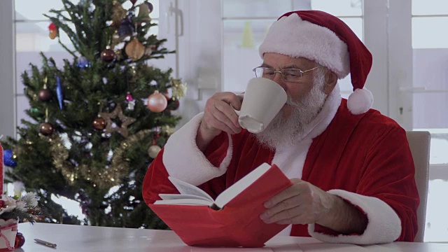 圣诞老人一边喝着杯子里的水，一边看书视频下载