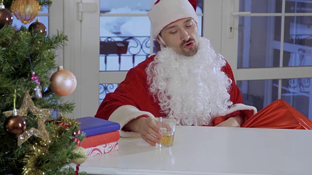 醉醺醺的圣诞老人坐在桌子旁喝威士忌视频下载