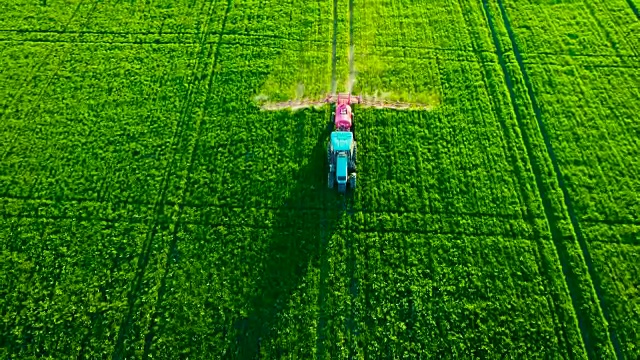 农用拖拉机在田间耕作和喷洒的鸟瞰图视频素材