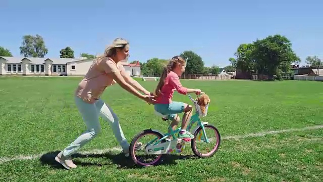 妈妈陪女儿玩，教她骑自行车视频素材