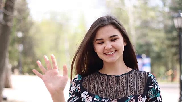 快乐的20岁年轻女子挥手告别或向镜头问好。女孩欢迎观众视频素材