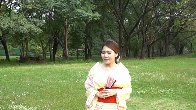 穿着和服穿过秋天的花园的女人视频素材