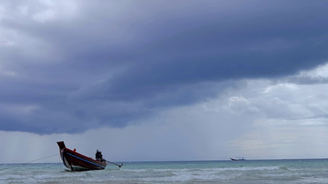 在浅海中，长尾船在海滩附近摆动。背景是泰国的风暴云视频下载