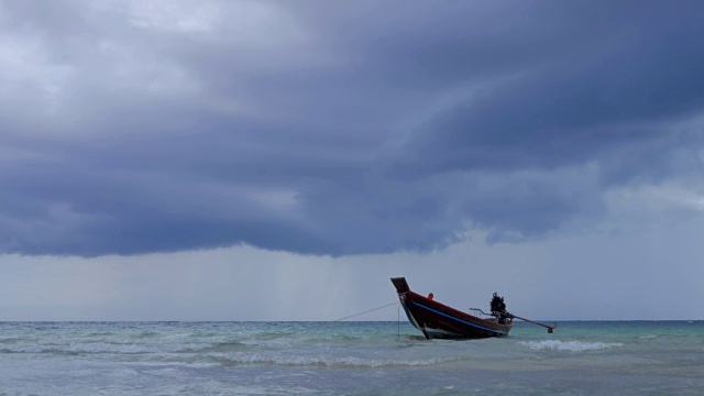 在浅海中，长尾船在海滩附近摆动。背景是泰国的风暴云视频下载