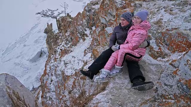 一对年轻夫妇喜欢在冬季的山顶户外散步。活跃的情侣走过冬日，美丽的冬日。几个徒步旅行者在雪山间的小径上散步。视频下载