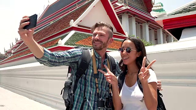 一对游客情侣在泰国的泰国寺庙用智能手机自拍视频素材