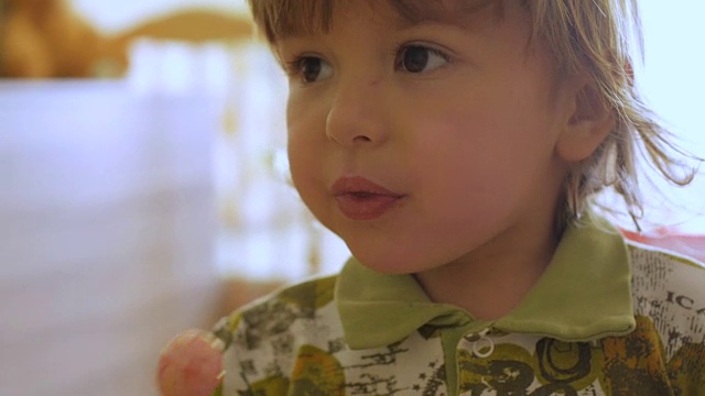 小男孩一边盯着镜头一边享受棒棒糖。孩子吃糖果，糖果，糖视频下载