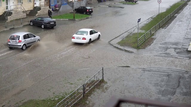 汽车在雨中行驶在被洪水淹没的道路上，慢镜头。视频素材