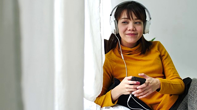 一个年轻女子戴着耳机听音乐的慢动作场景视频素材