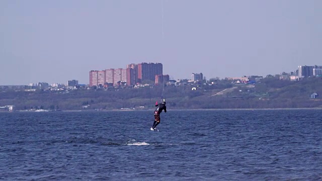 慢动作:一名男子的风筝滑板越过一条大河的水面。水花四溅向不同的方向。阳光明媚的春天。视频素材