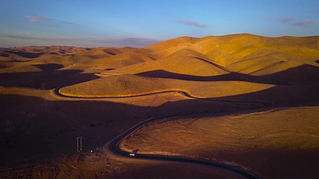 汽车行驶在沙漠道路上的鸟瞰图在日落时的蓝天，Taghazout，摩洛哥视频下载
