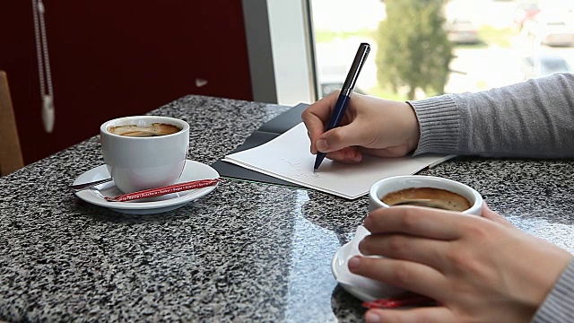 女人手捧咖啡，在咖啡馆里写商务每日计划视频素材