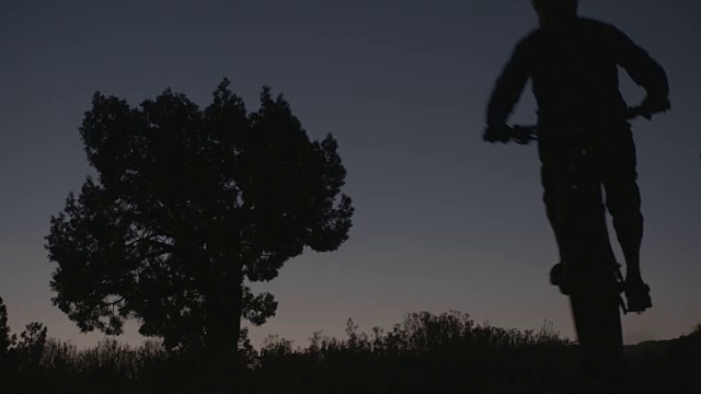 一个男人骑着山地车下山在沙漠中的剪影视频素材