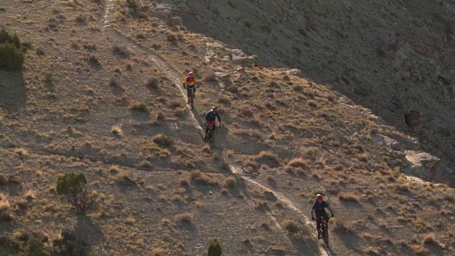 四个骑山地自行车的人从一座沙漠山上下来视频素材