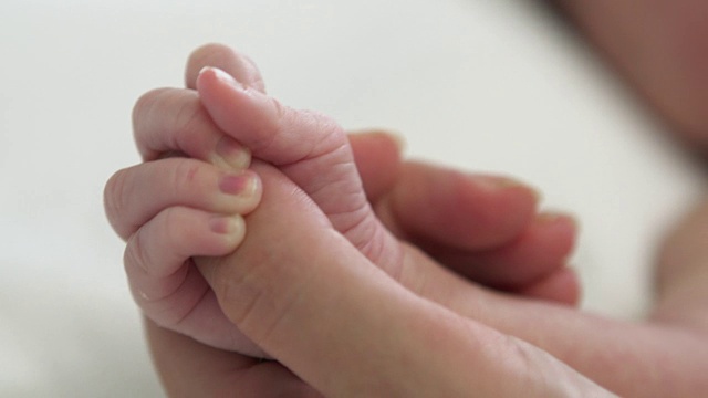 CU新生婴儿的手握着妈妈的手指视频素材