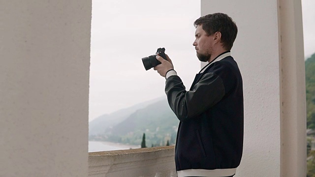 男摄影师在镜头里看着一幅风景视频下载