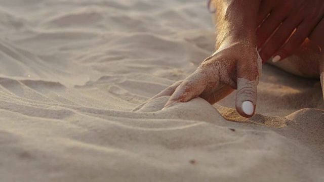 身份不明的年轻女孩的手触摸沙子视频素材