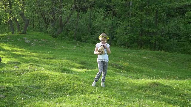 金发小女孩抱着她的宠物豚鼠。手持平滑的镜头外面。夏季。视频素材