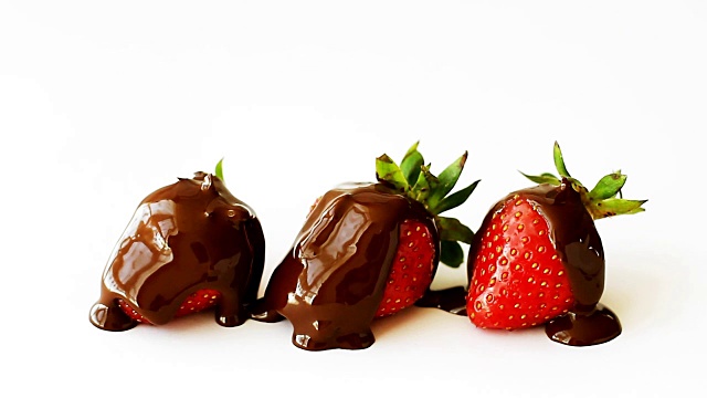 三颗成熟的草莓淋上融化的巧克力，孤立在白色的背景上视频素材