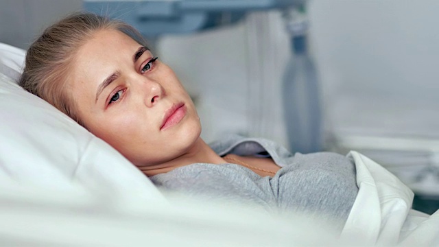 一个年轻的女病人躺在病房里。伤心难过的女人在想现代诊所的生活视频下载