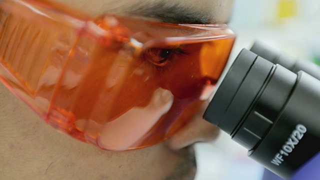 在实验室里观察显微镜的研究人员，概念科学视频购买