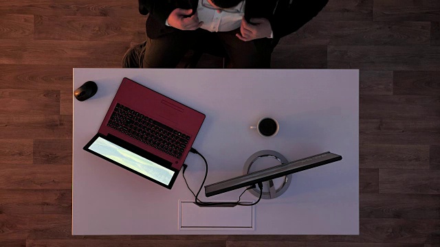 一个年轻人在笔记本电脑上打字，然后拿起他的闪存盘，当灯打开时，导演进来了，上面的照片视频素材