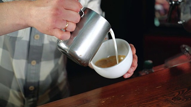 咖啡师制作拿铁艺术图片叶子和心在咖啡馆热咖啡。视频下载