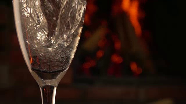 香槟被倒进一个以火为背景的玻璃杯中视频下载