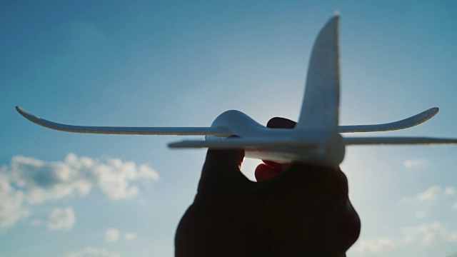 手里拿着一架玩具一样的飞机冲向天空，冲向天空。梦想和良好的创业理念视频素材