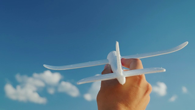一个男人的手拿着一架玩具飞机飞向天空。创意和梦想的商业理念视频素材
