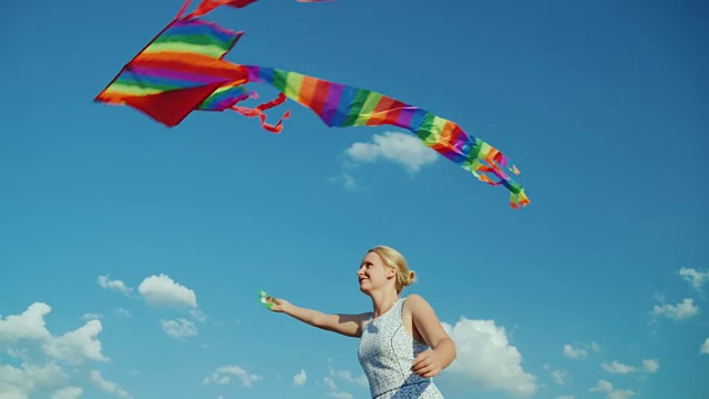 快乐的女人小时候在纯净的蓝天下玩着风筝视频素材