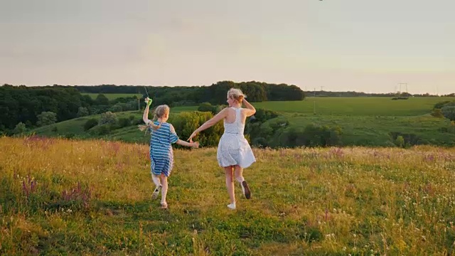 一个年轻的女人和她的女儿放了两只风筝，玩得很开心，享受着活跃的假期视频素材