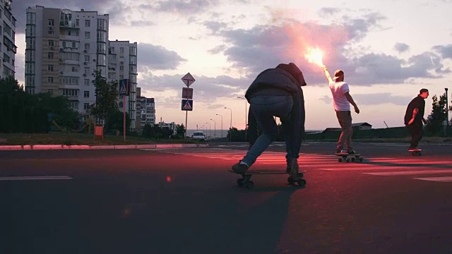 一群年轻人在清晨的马路上玩滑板，伴随着红色的信号弹，慢动作视频素材