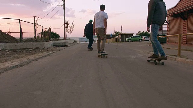 清晨一群年轻人在海边的路上玩滑板，近景拍摄视频素材