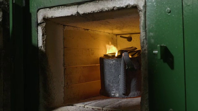 近距离女子铁匠的手检查铝和火焰从一个熔化的回收炉炉内，然后关闭它视频素材